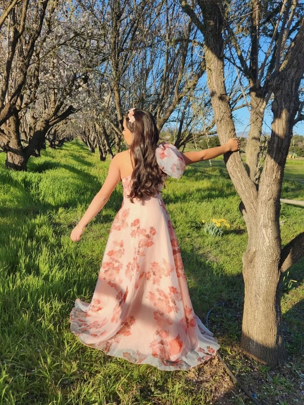 Anelly stands outside in her cherry blossom dress.